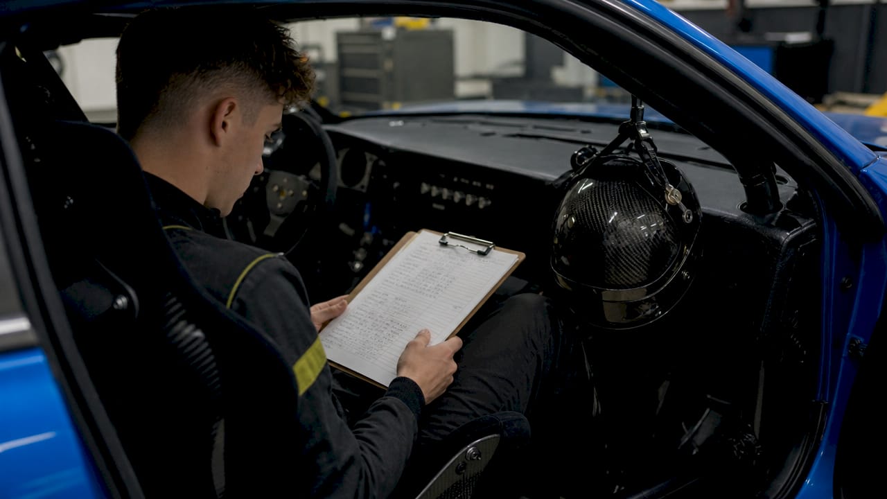 Hands writing suspension tuning notes inside race car
