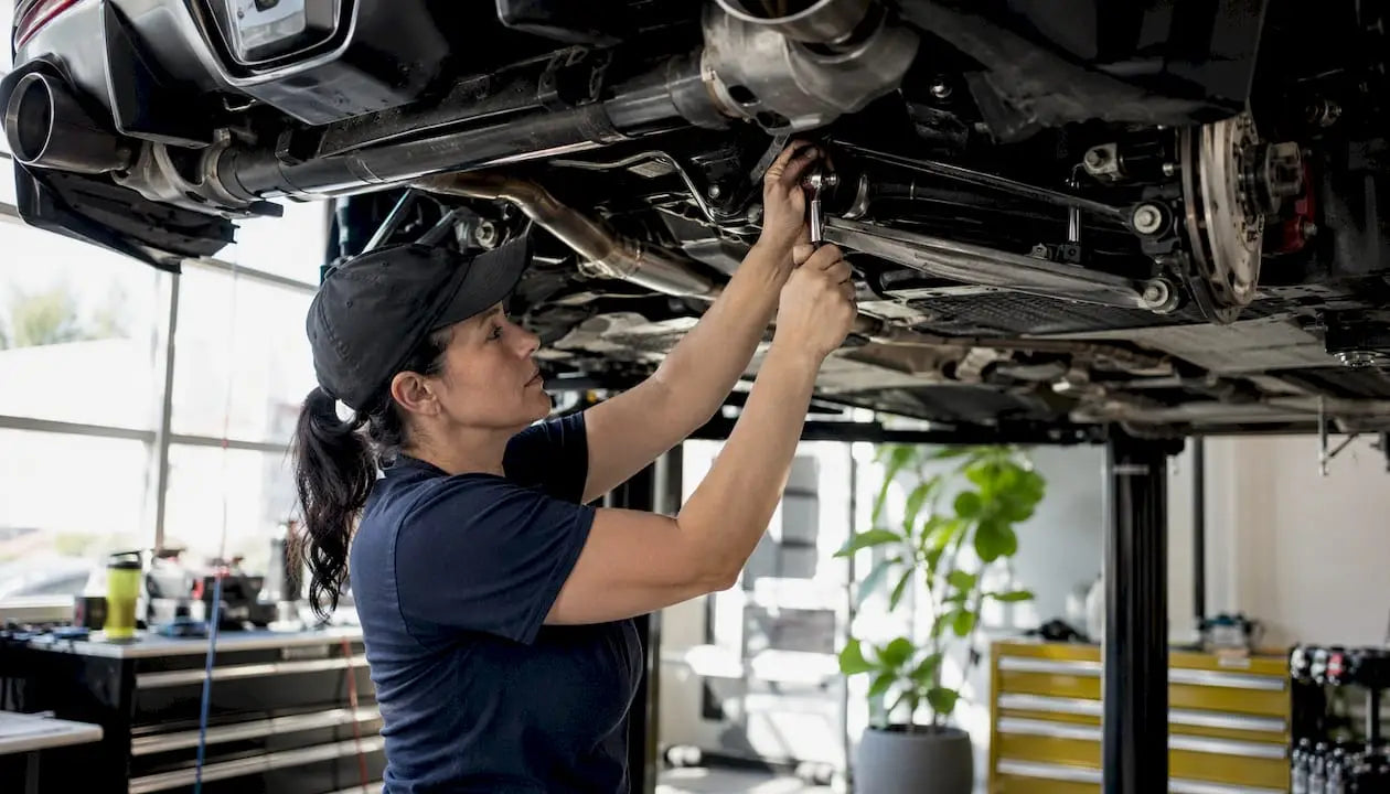 Mechanic tightening sway bar end links under Toyota Supra