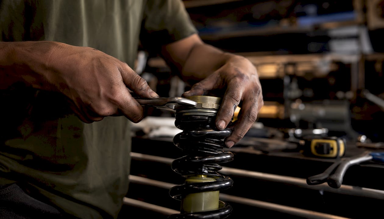 Hands assembling coilover hardware with wrench