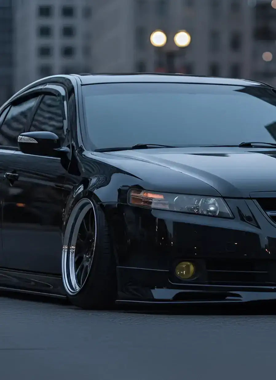 Black acura tsx with lowered suspension and custom multi-spoke alloy wheels.
